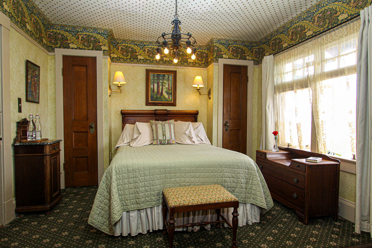 Guest room with bed, dresser appointed with lovely wallpaper